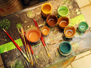 Many brushes and glass jars with ceramic colored pigments prepared to paint tiles by hand in the...