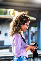 Young girl walking alone on train platform and taking photos on railway station
