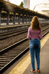 Young girl walking alone on train platform and taking photos on railway station
