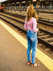 Young girl walking alone on train platform and taking photos on railway station