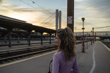 Young girl walking alone on train platform and taking photos on railway station