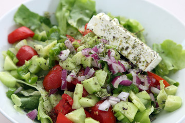 Greek salad with lettuce, tomatoes, cucumbers, peppers, red onion, oregano and feta