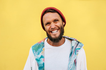 Stylish young hipster man with beard in red hat and a retro jacket of 90s on yellow background.Crazy hipster guy emotions. Collage in magazine style .