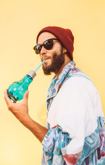 Stylish young hipster man with beard in red hat and a retro jacket of 90s on yellow background....