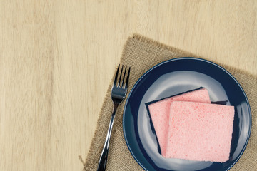 Top view of pink milk flavored sandwich bread on blue ceramic plate and wooden background, warm tone.