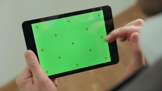 Male hand touching green screen tablet. Close up green chroma key tablet screen