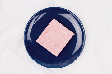 Top view of pink milk flavored sandwich bread on blue plate and white cloth background, soft warm tone, Beautiful breakfast concept.