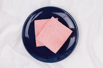 Top view of pink milk flavored sandwich bread on blue plate and white cloth background, soft warm tone, Beautiful breakfast concept.