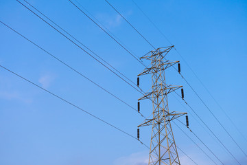 High voltage electricity pylon on blue sky.