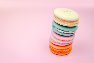 Colorful french macarons (macaroons) cake,  delicious sweet dessert on a pink background with copyspace, food background concept.
