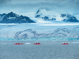 A group of tourists in red kayaks near the Jökulsárlón glacier lagoon.