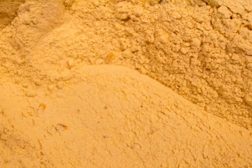 ground corn in a wooden trunk next to a wooden shovel