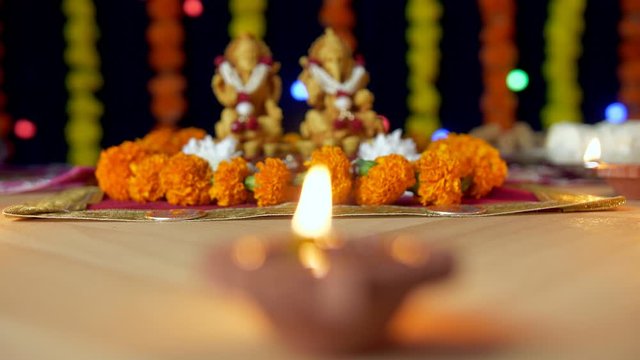 Bokeh shot - Burning Diya with Indian gods Ganesh Ji and Laxmi Ji - Indian festival Diwali . Closeup shot of a clay oil lamp with Lord Ganesha and Goddess Lakshmi kept on a floral platform for Diwa...