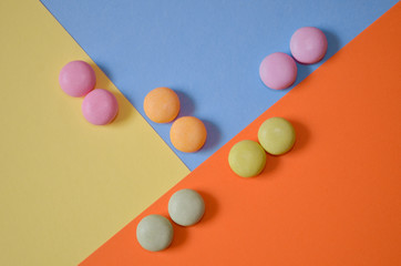 Round colored candies lie in pairs on three colored triangles, geometric background