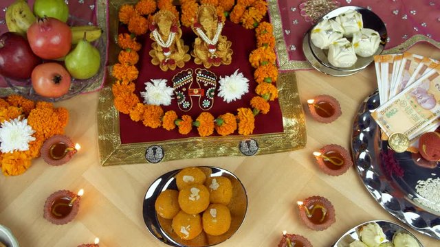 Top view of a decorated temple of Ganesh Ji and Laxmi Ji on the Indian festival Diwali. Lord Ganesha and Goddess Laxmi surrounded by sweets  fruits  dry fruits  oil lamps  Indian rupee notes  flowe...