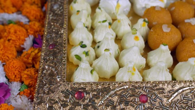 Closeup shot of mix mithai served in a beautiful silver tray on the festival of Diwali. Modak  Bundi Laddu/Motichoor  Chamcham in a rotating decorated plate kept on turntable for Diwali/ Deepavali ...