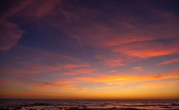 Beautiful, vivid sunset sky over ocean with red clouds and blue yellow gradient background
