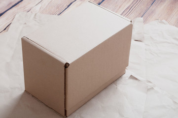 Brown carton box laying on sheets of crumpled kraft paper.