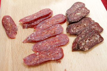 Jerky, biltong, jerk, jerked meat on a wooden board. Dry meat pattern. Flat dry sausage.