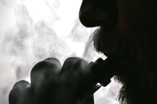 Man with concealed identity smoking a controversial vape is a health risk