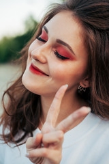portrait of a beautiful girl with bright makeup shows two fingers