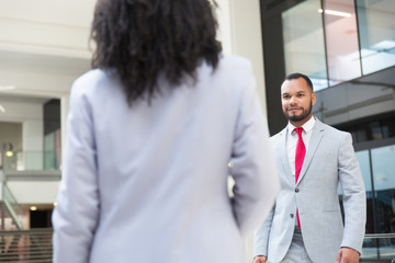 Fototapeta premium Happy friendly businessman going to meet his female colleague. Business man walking through hallway to woman in office suit. Partnership concept