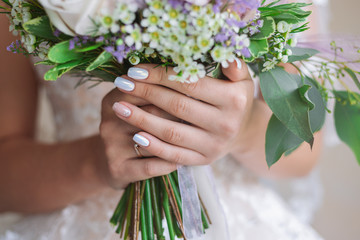 Close-up view of hands of young white bride holding bridal bouquet. Beautiful two colours shiny...