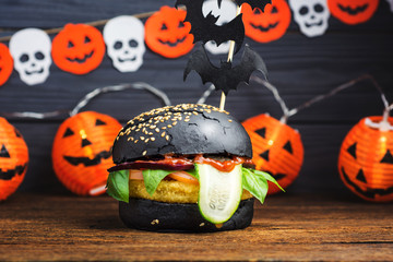 Halloween Spooky Black Burger with Cheese. Cheeseburger on Halloween pumpkin head jack lantern background