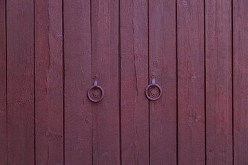 The wooden facade of the wall is painted red with forged handles in the view of the rings.