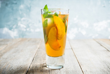 Tasty peach tea in glass on the rustic background. Selective focus. Shallow depth of field.