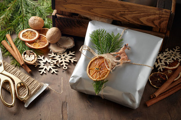 Packaging christmas present handmade gift boxes decorated with silver paper with dried orange slices
