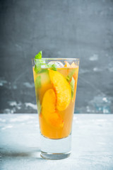 Tasty peach tea in glass on the rustic background. Selective focus. Shallow depth of field.