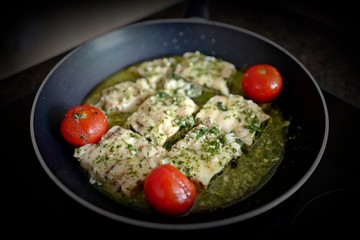 cooking at home - roast fish with cherry tomatoes, dill and olive oil in a hot pan