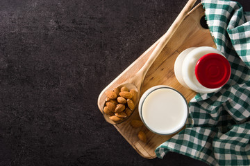 Almond milk in glass and bottle on black background. Top view. Copy space