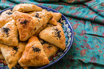 Uzbek Samsa or Sambousak in national plate. Samsa or Sambousak an oriental meal to be stuffed with minced meat, cheese or vegetables. The national dish of Uzbekistan and Central Asia.