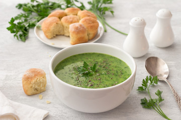 Healthy green kale cream soup with potatoes and bread on gray background. simple homemade food