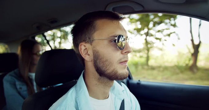 Young boyfriend and girlfriend in casual outwear and sunglasses driving car in countryside, travelling