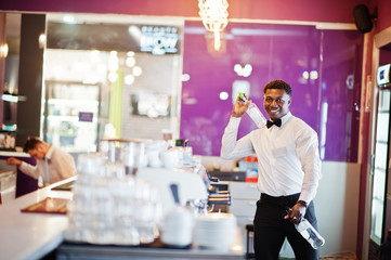 Fototapeta premium African american bartender at bar flair in action, working behind the cocktail bar. Alcoholic beverage preparation.