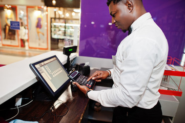 African american bartender at bar uses a calculator on cashier.