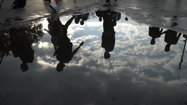 Reflections on puddle and legs of the walking people