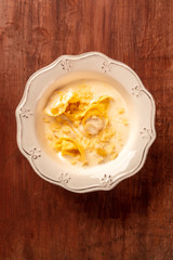 Italian tortellini with a cream sauce and grated Parmesan cheese, shot from the top on a dark rustic wooden background with a place for text