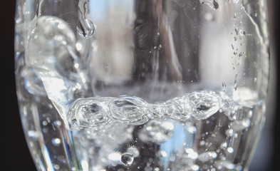 Pouring water into glass on black background