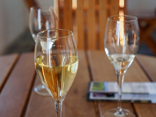 Closeup detail of multiple glasses of sparkling and white wines on a wooden table during a tasting session at a winery. Nanstallon, Bodmin, England. Travel and Cornish wine industry.
