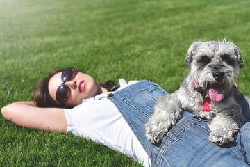 Pretty adult caucasian happy woman resting in the park on a sunny day with her beloved dog. Female...