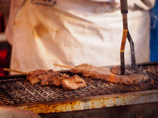 Pressing beef skewers, Yakiniku Kushiyaki, roasted with a meat press over a flaming charcoal grill. Omiya, Saitama, Japan. Travel and street food.