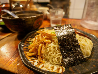 Wide closeup of Tsukemen ramen noodles, with bamboo sprouts. seaweed, and dipping sauce, on a...
