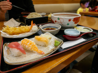 Wide closeup of a lunch set with Tempura fried shrimp, Salmon, Maguro, and Ebi Nigiri Sushi, and Soba noodles. Narita, Chiba, Japan. Travel and cuisine.