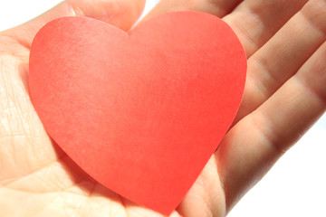 Obraz premium A bright red heart made of paper lies on the palm of your hand.