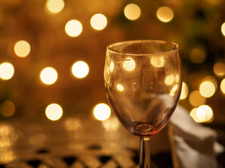 Closeup detail of an empty wine glass reflecting beautiful yellow lights of a pub in the background. Shallow Bokeh focus. London, England. Party and night life.