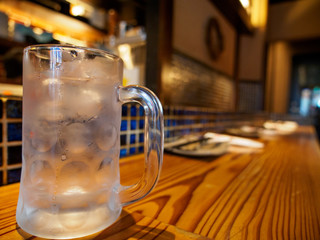 Wide closeup of a empty beer mug with condensation on a wooden counter at an Izakaya bar. Namba, Osaka, Japan. Travel and cuisine.